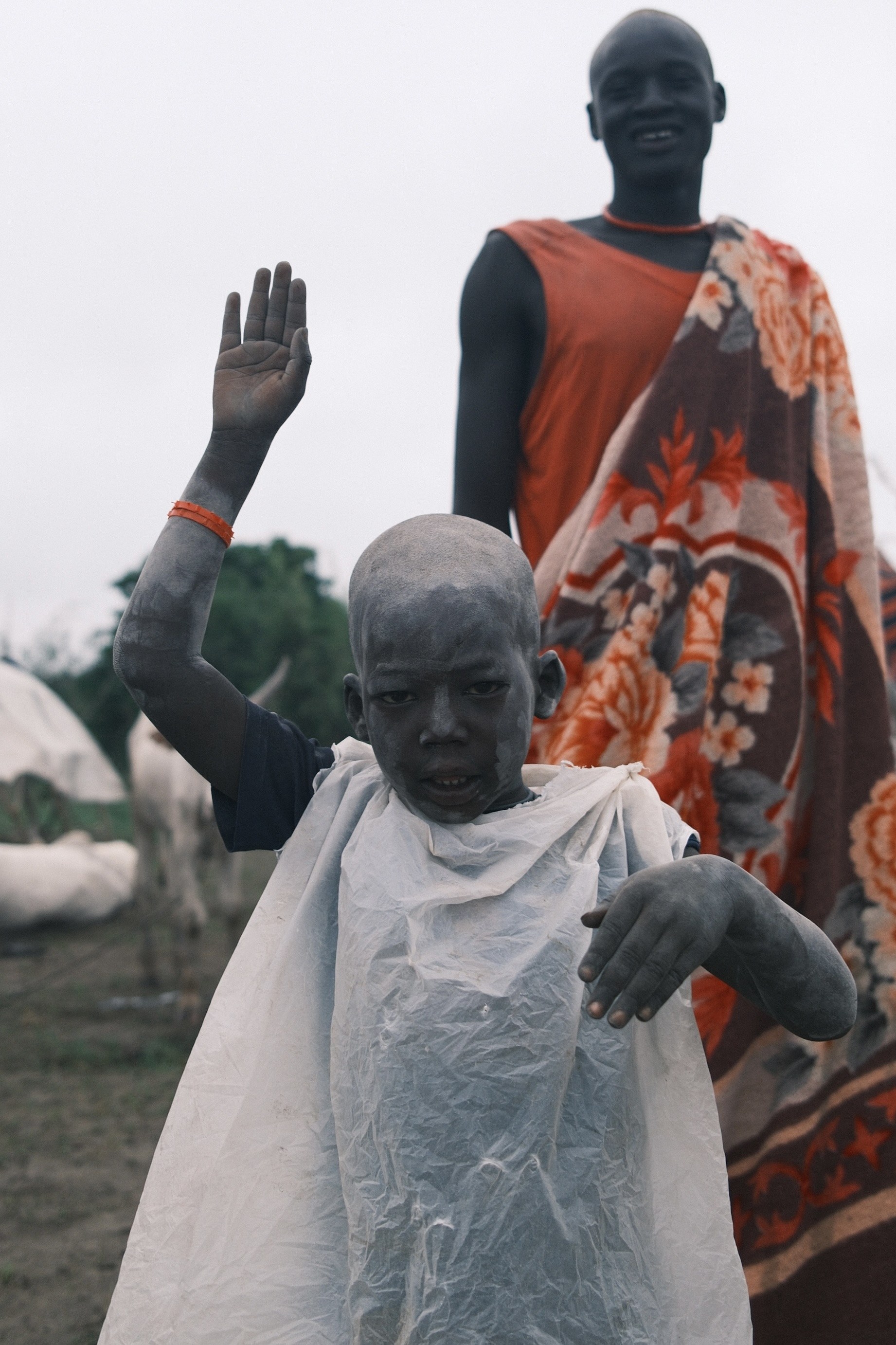 Ash-dusted boy waving, cattle camp
